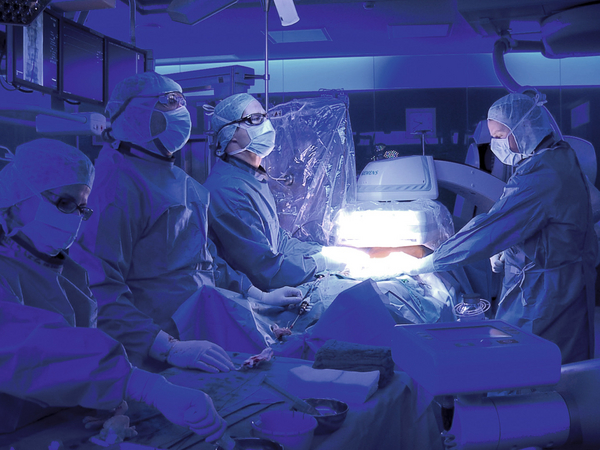 Ein Operationsteam der Gefäßchirurgie um Dr. med. Lars Kock arbeitet im dunkelblau beleuchteten Hybrid-Operationssaal während einer Operation mit einem hell beleuchteten Operationsfeld im Albertinen Herz- und Gefäßzentrum in Hamburg Ein Operationsteam der Gefäßchirurgie um Dr. med. Lars Kock arbeitet im dunkelblau beleuchteten Hybrid-Operationssaal während einer Operation mit einem hell beleuchteten Operationsfeld im Albertinen Herz- und Gefäßzentrum in Hamburg